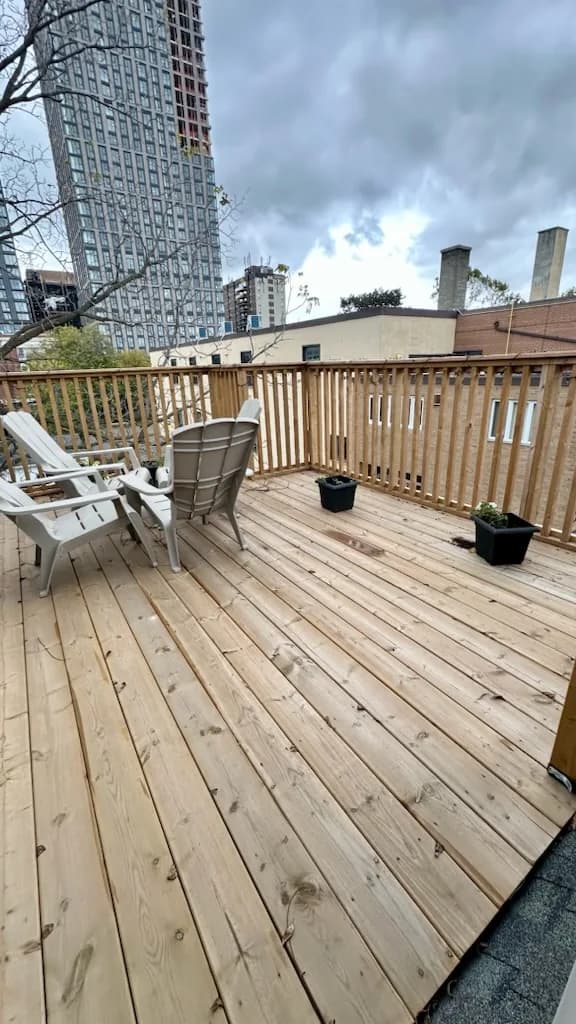 After: the rooftop deck rebuilt with new wood boards and railing, chairs back in place, by Task Magic Handyman